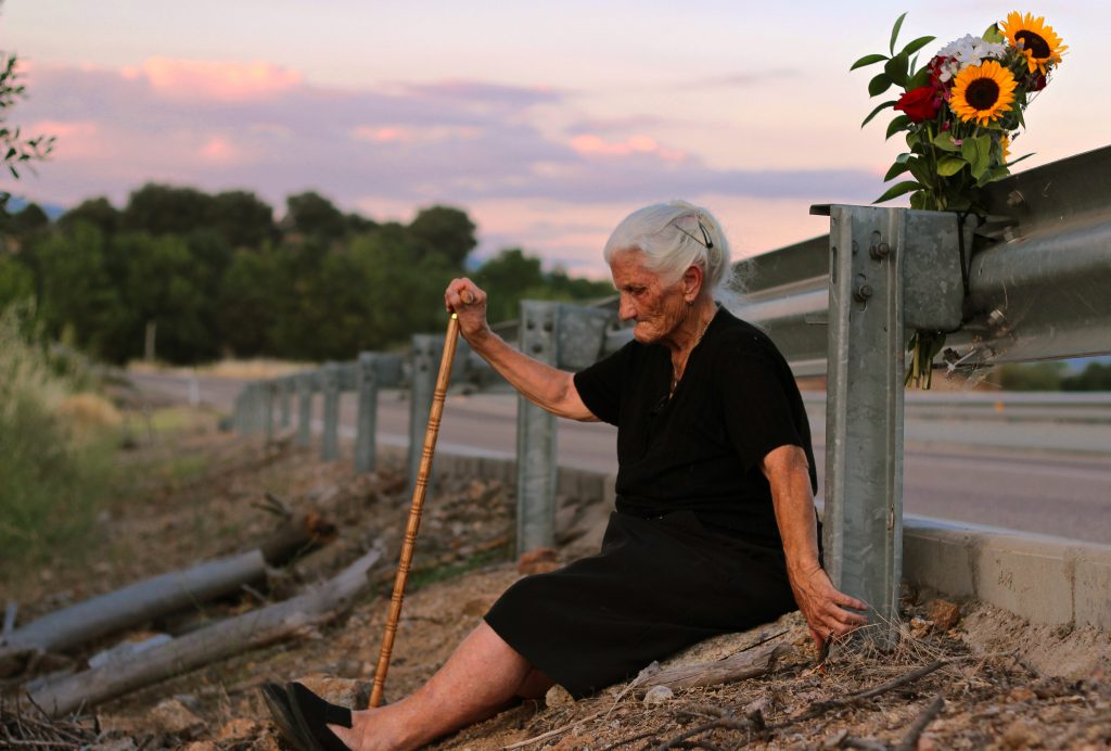 Une vieille femme assise sur le bord d'une route - Photographie du film Le Silence des autres