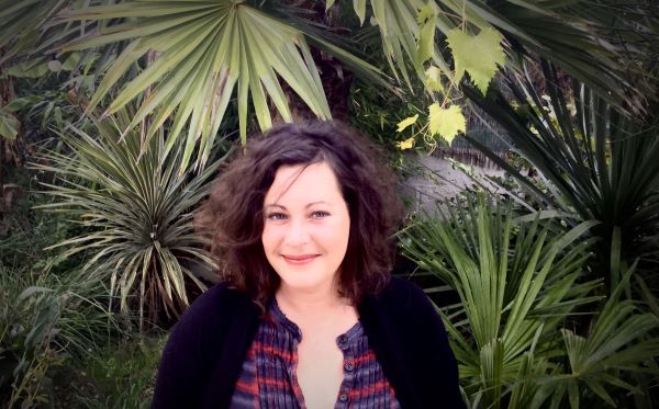 Portrait de la réalisatrice Amélie Harrault devant des feuilles de palmier