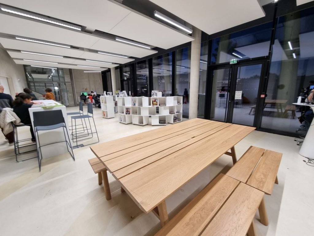 Photographie de l'espace café social avec de grandes tables à pique nique