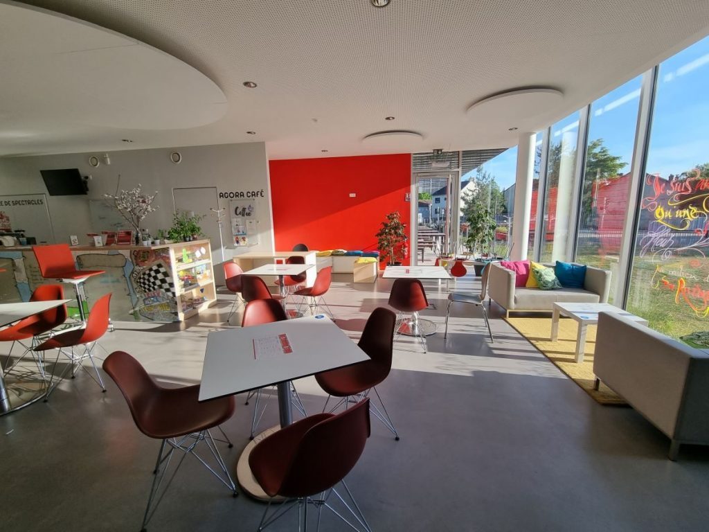 Photographie des tables et chaises disposées dans l'Agora café
