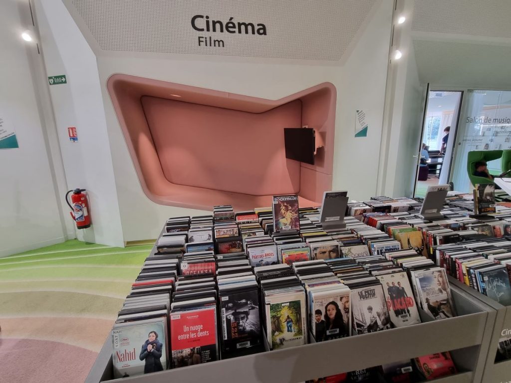 Photo de l'espace cinéma avec les bacs de DVD et derrière l'alcôve dans le mur avec un écran pour leur visionnage