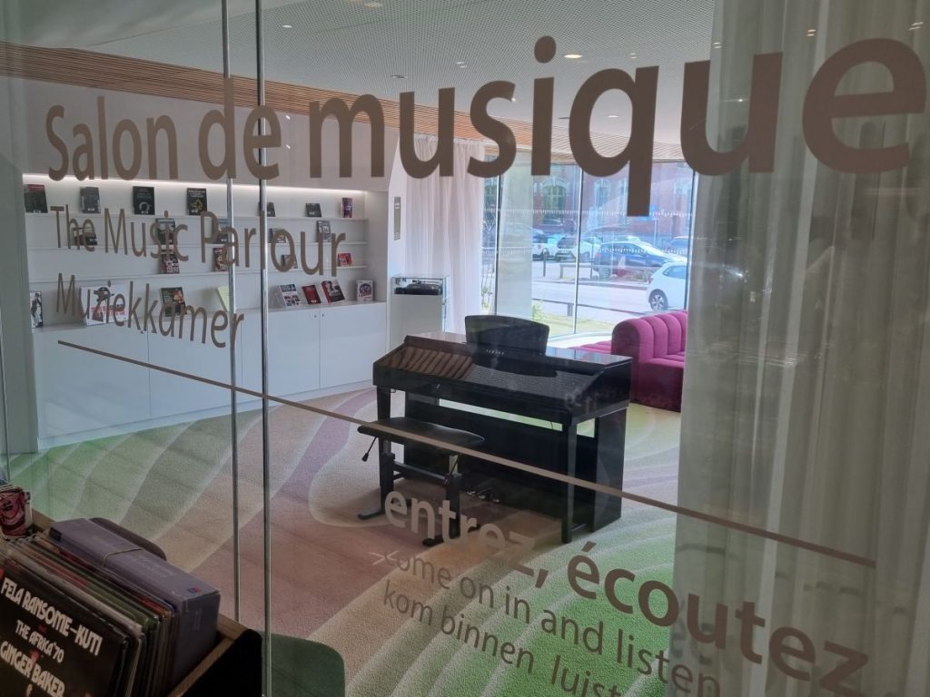 Photo du salon de musique avec un piano et les bacs à vinyles devant
