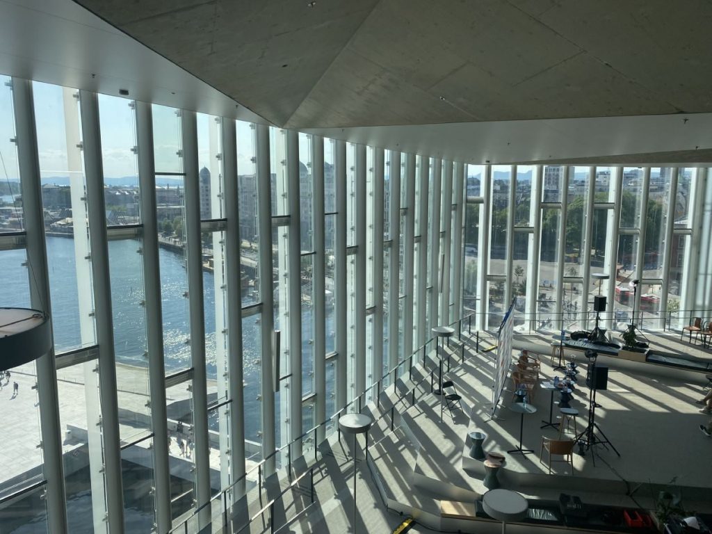 Espace intérieur de la Deichman Bjorvika Bibliotek : immense baie vitrée donnant sur le port, scène modulable © Bpi