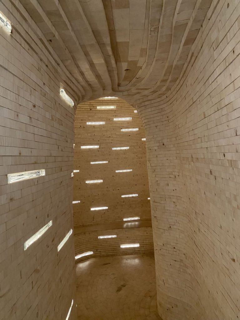 Photo de la Future Librairy : couloir courbe composé de briques de bois, intercalée de briques lumineuses en verre où seront déposés les manuscrits jusqu'en 2114 © Bpi