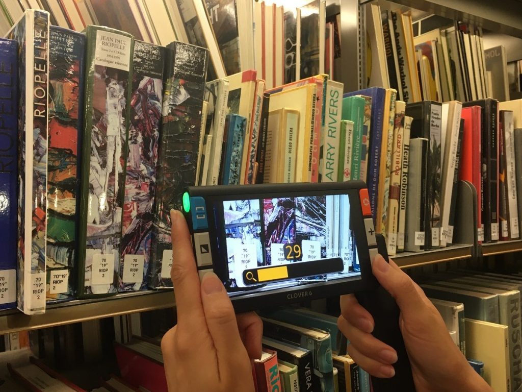 Utilisation d'une loupe électronique pour lire les cotes des livres dans la bibliothèque.