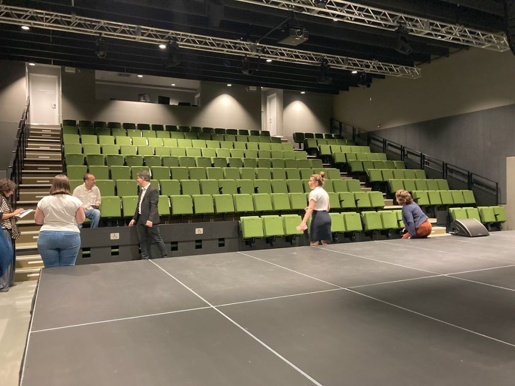 Grande salle de spectacle avec gradins verts