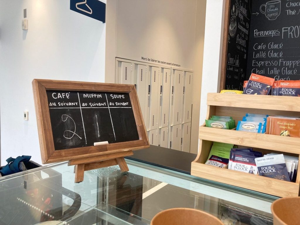 Tableau noir installé dans l'espace café de la bibliothèque avec écrit à la craie : "café au suivant : 2"; "Muffin au suivant : 1"