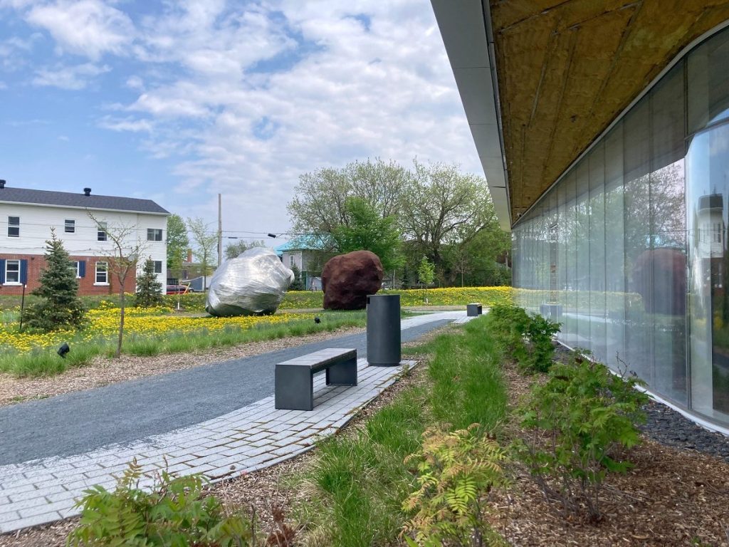 Façade vitrée de la bibliothèque et œuvre d'art dans l'herbe consistant en deux formes d'œuf métalliques