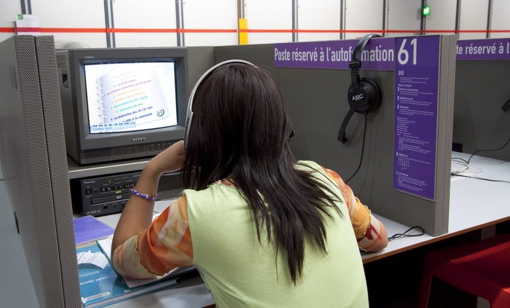 Une jeune femme consulte un poste informatique dans une cabine de l'espace Autoformation de la Bpi