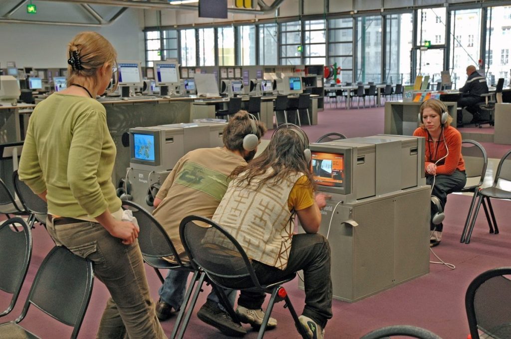 Des usagers assis regardent la télévision dans l'espace Autoformation de la Bpi