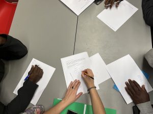 Plan sur les mains de jeunes qui écrivent des fiches lors d’un atelier d’alphabétisation