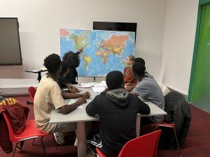 De jeunes mineurs non accompagnés en situation d’exil sont assis autour d’une table lors d’un atelier sur les savoirs de base