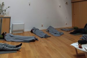 Des étudiants font la sieste allongés sur des tapis au sol et enroulés dans des plaids