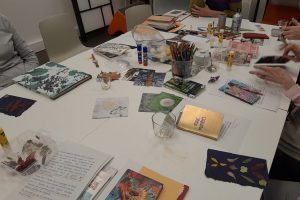 Table avec des livres, des crayons et du matériel créatif pour un atelier de bibliothérapie sur le thème du jardin.