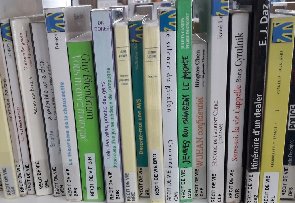 Étagère de livres étiquetés avec le pictogramme bleu représentant le drapeau des Sourds
