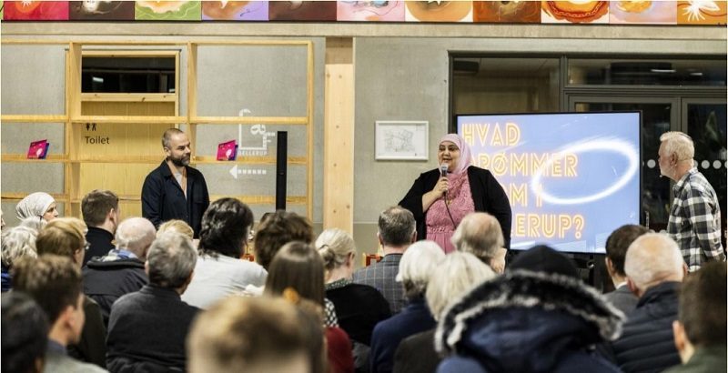 Deux intervenants débattent face au public dans la bibliothèque