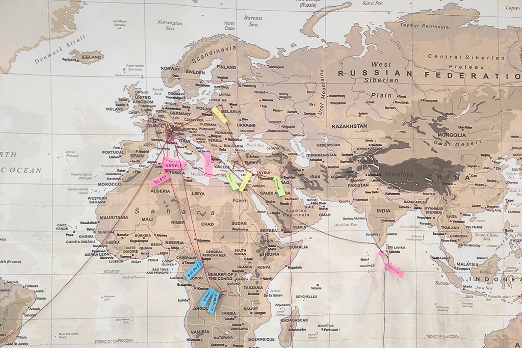 Planisphère avec des épingles et des fils reliant les épingles entre elles pour indiquer les parcours de vie des participants à l'atelier