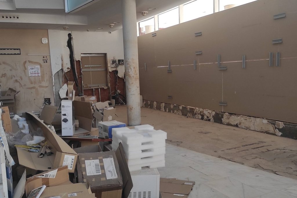Intérieur de la bibliothèque de Paiporta pendant les travaux post-inondation : murs endommagés, cartons et matériel entreposés au sol.