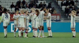 photo représentant l'équipe féminine de football de Lyon sur le terrain en train d'échanger.