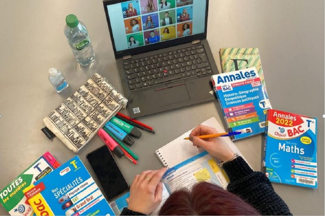 Table de révisions avec ordinateur, annales du bac, crayons.