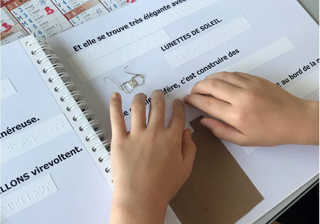 Des mains découvrent un livre tactile.