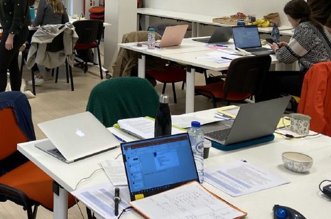 Tables de travail des étudiants, avec ordinateurs et fiches de révision