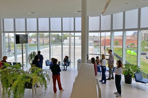 L'intérieur de la bibliothèque de Drummondville avec des personnes debout, devant une grande baie vitrée.