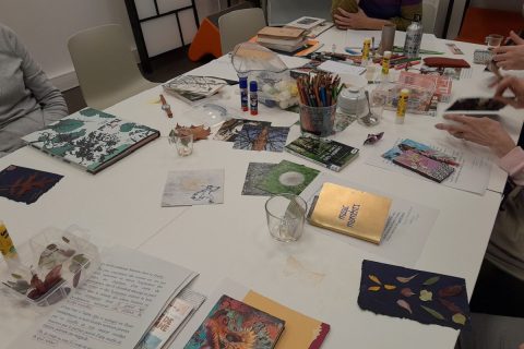 Table avec des livres, des crayons et du matériel créatif pour un atelier de bibliothérapie sur le thème du jardin.