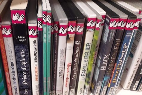Étagère de DVD étiquetés avec le pictogramme fushia représentant le handicap auditif - LSF