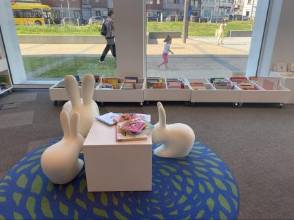Espace jeunesse de la bibliothèque comportant des bacs à albums devant une baie vitrée et du mobilier blanc en forme de lapins.