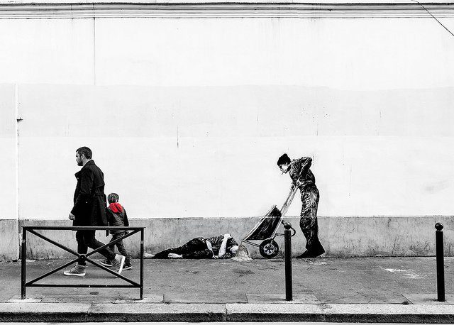 Passants devant une oeuvre de street art montrant un homme à terre